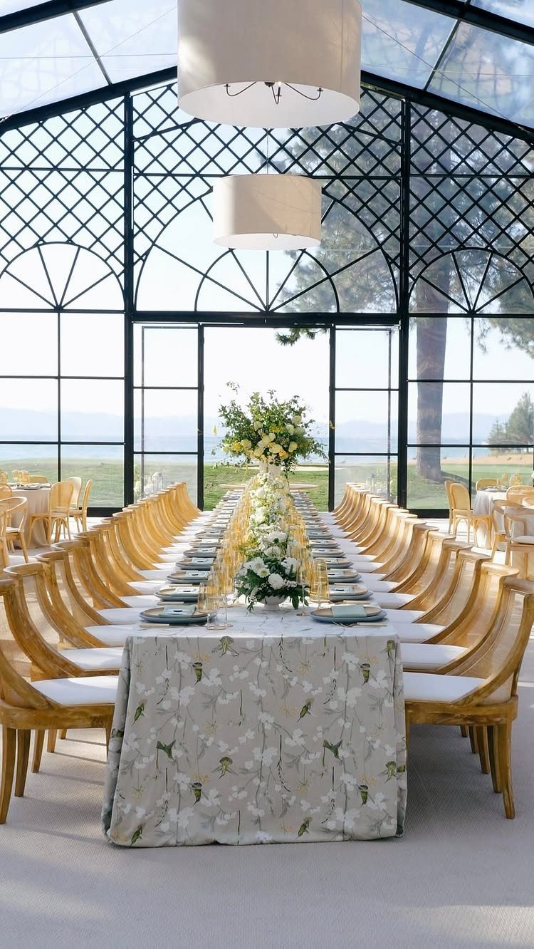 Long wedding reception table set inside a glass conservatory overlooking Lake Tahoe.