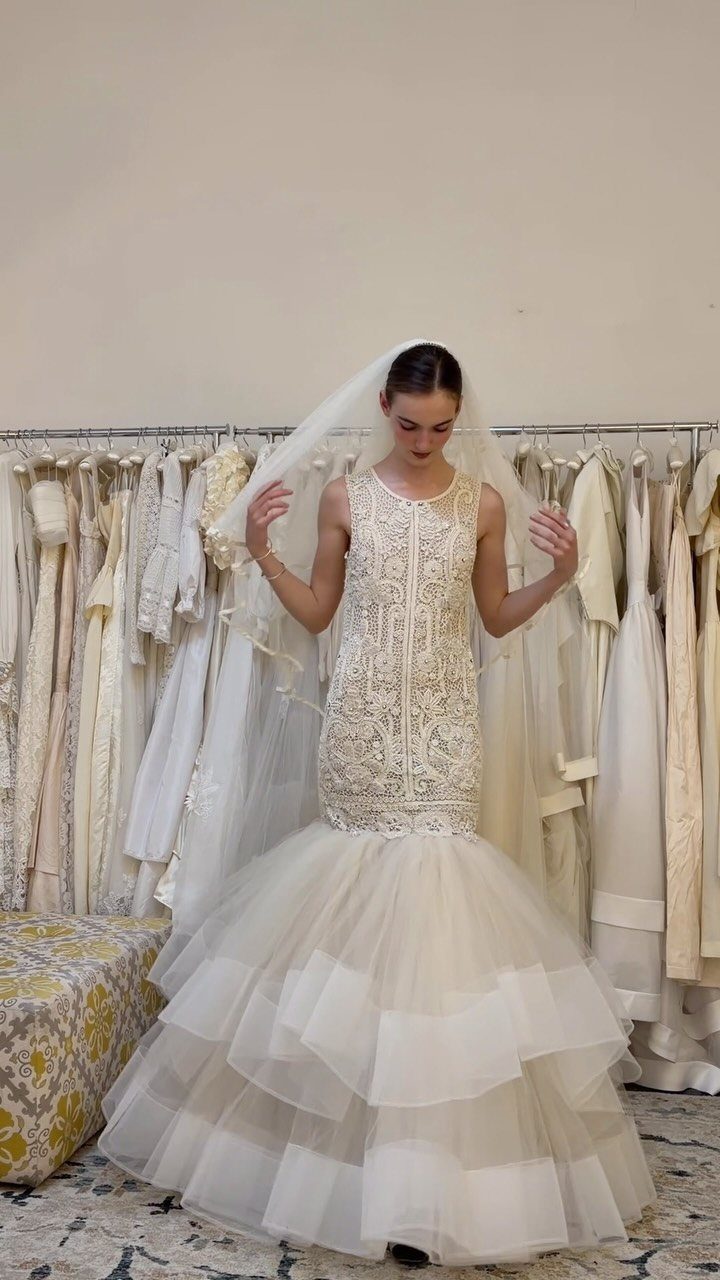 Woman in a white mermaid wedding dress with beaded bodice and tiered tulle skirt.