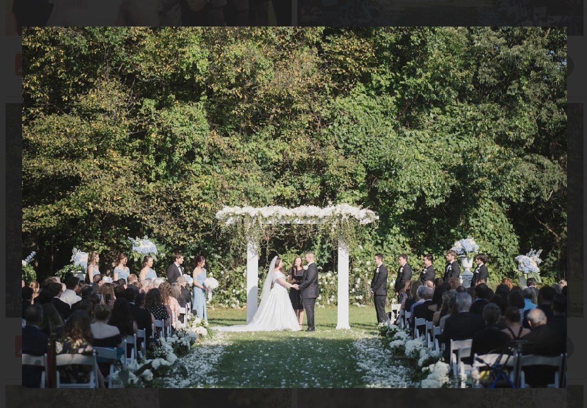 Wedding ceremony with a bride and groom under a floral arch in a garden.