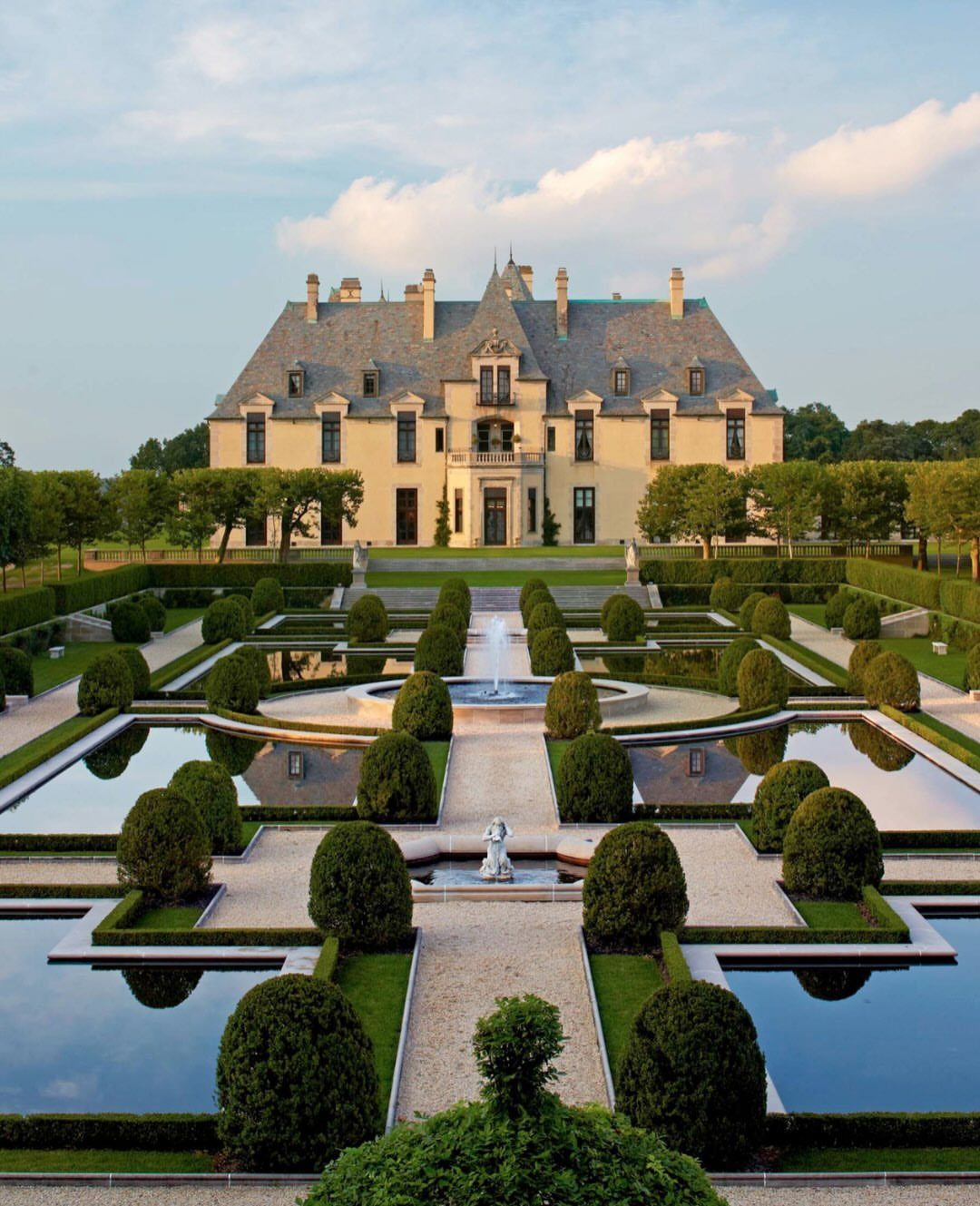 Oheka Castle mansion with symmetrical formal gardens, reflecting pools, and manicured green hedges.