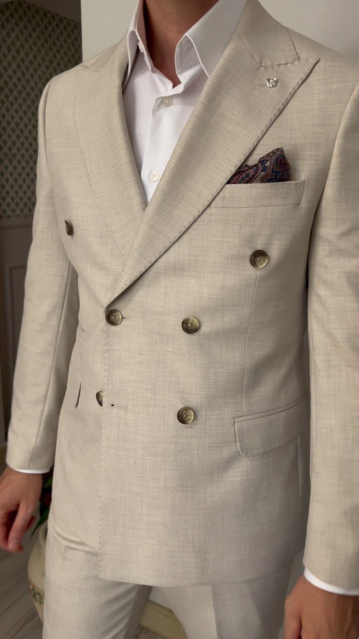 Man wearing a light beige double-breasted linen suit with a white shirt.