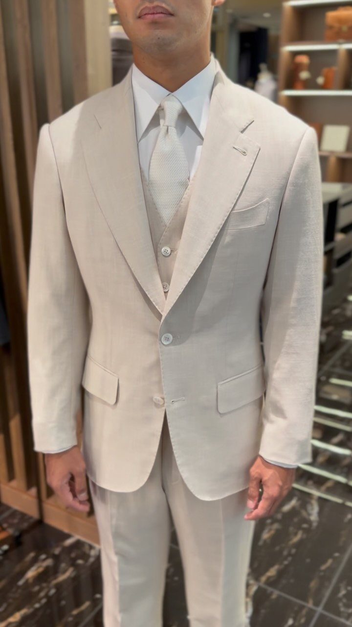Man wearing a light beige linen three-piece suit with a matching tie.