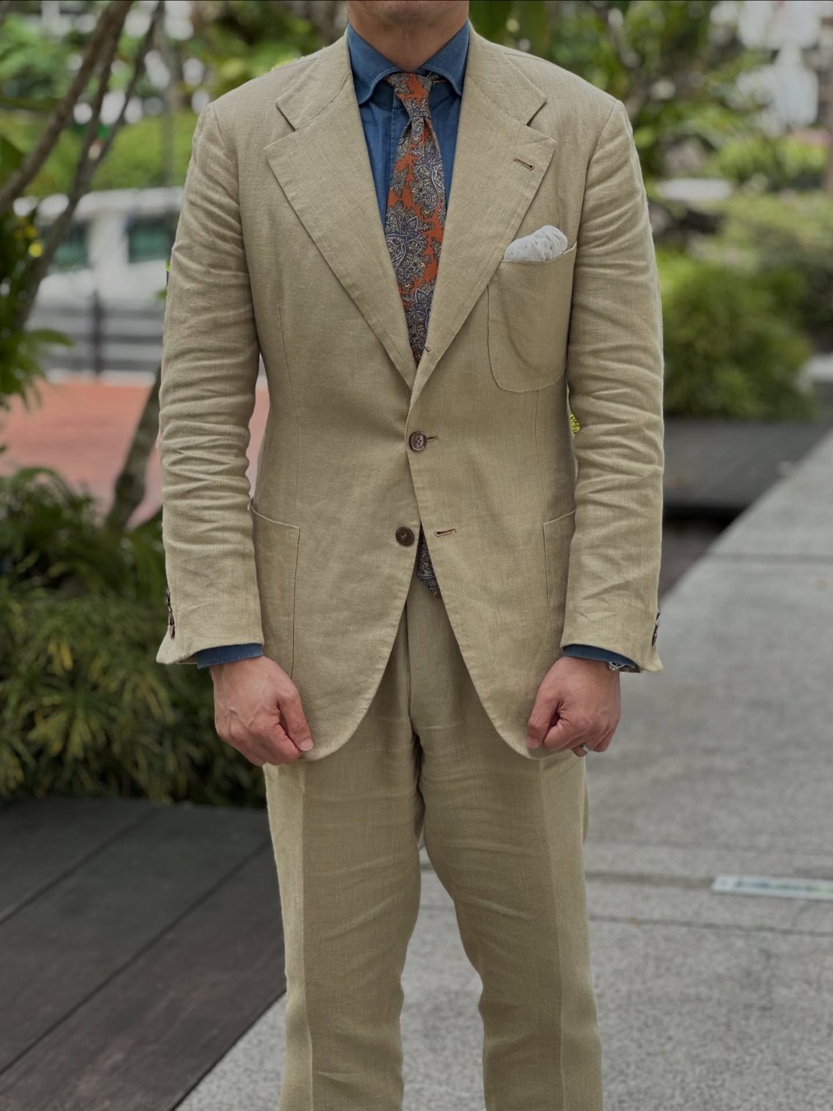 Man in a beige linen suit showing natural fabric wrinkles and creases.