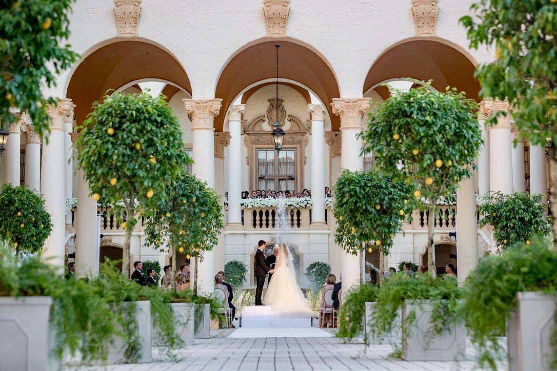 Bride and groom at a wedding ceremony in a Mediterranean style courtyard with lemon trees.