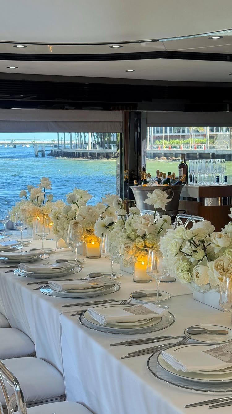 Elegant wedding table setting with white flowers and candles aboard a luxury yacht.