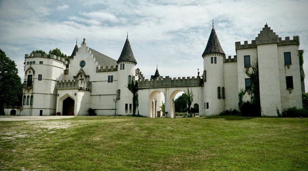 White castle venue with turrets and battlements overlooking a wide green lawn