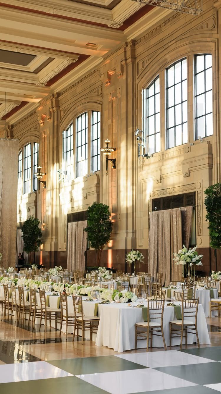 Grand ballroom with white clothed tables and gold chairs in a historic station.