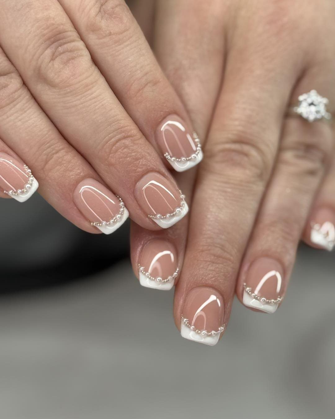 French manicure with white tips and small silver beads on square nails.