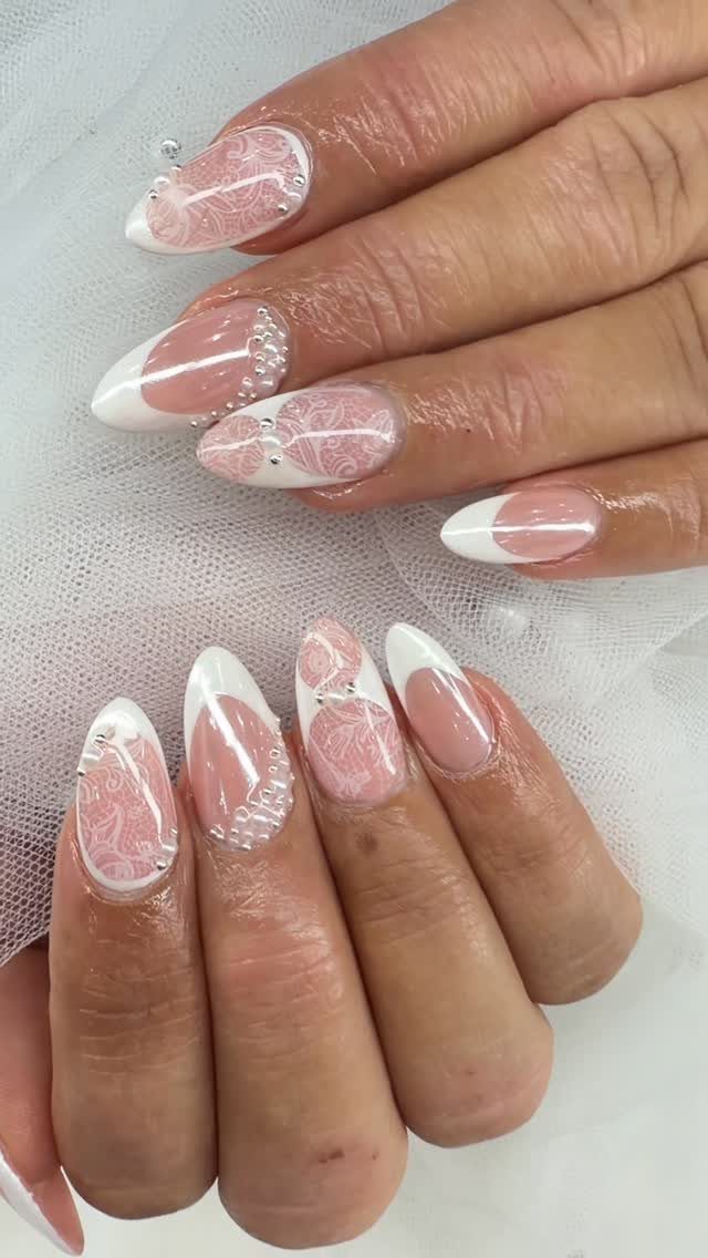 Almond nails with white lace patterns, French tips, and small pearl accents.