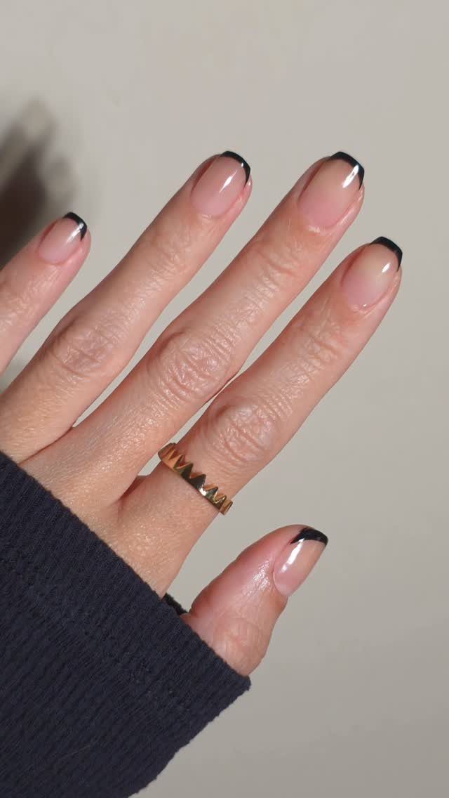 Almond nails with nude base and thin black micro french tips and gold ring
