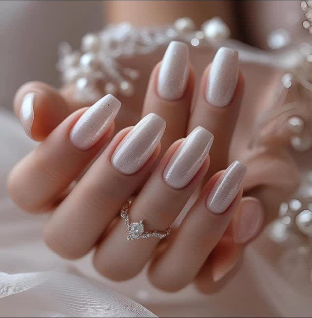 Pearlescent milky white square nails with a diamond ring and pearl accessories.