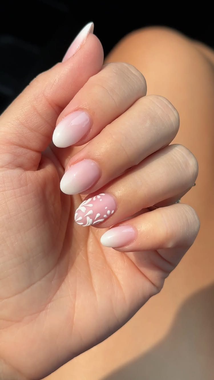Almond shaped nails with pink and white ombre gradient and floral nail art.