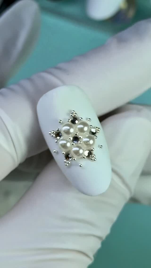 Matte white oval nail decorated with a cluster of small pearls and rhinestones.