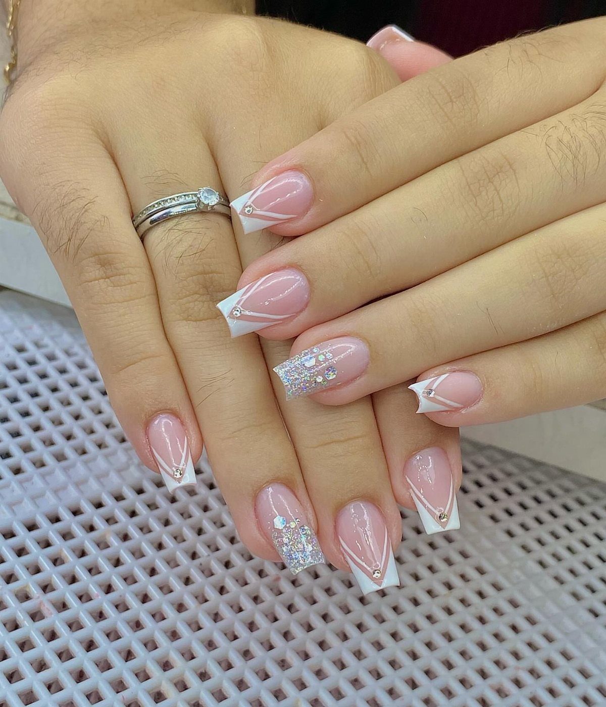 Square shaped bridal nails with white French tips and silver glitter accents.