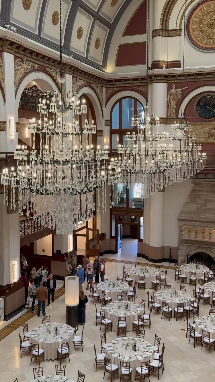 Grand hotel lobby with vaulted ceilings, crystal chandeliers, and white banquet tables.