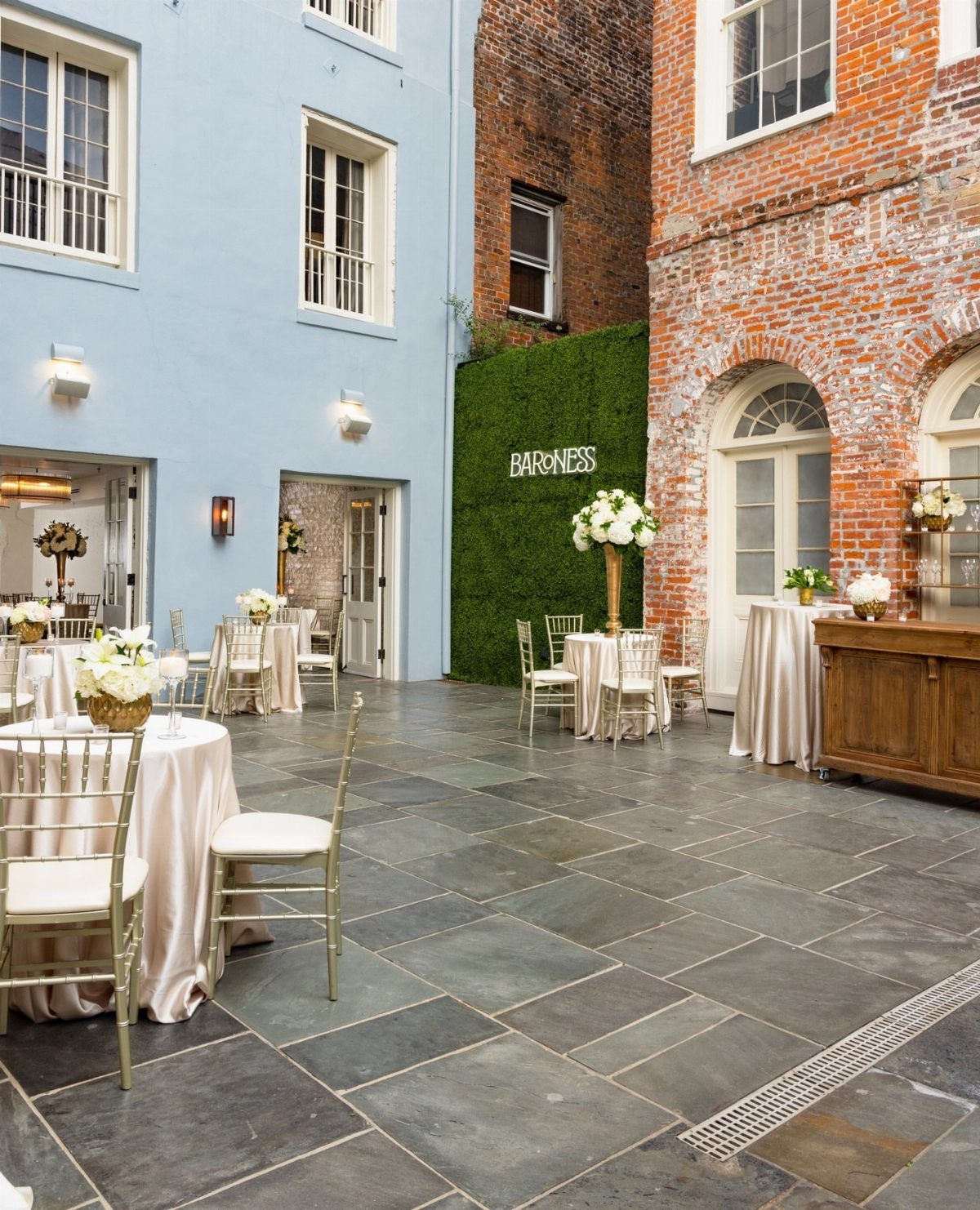 Courtyard at Baroness venue with champagne draped tables and white floral arrangements.