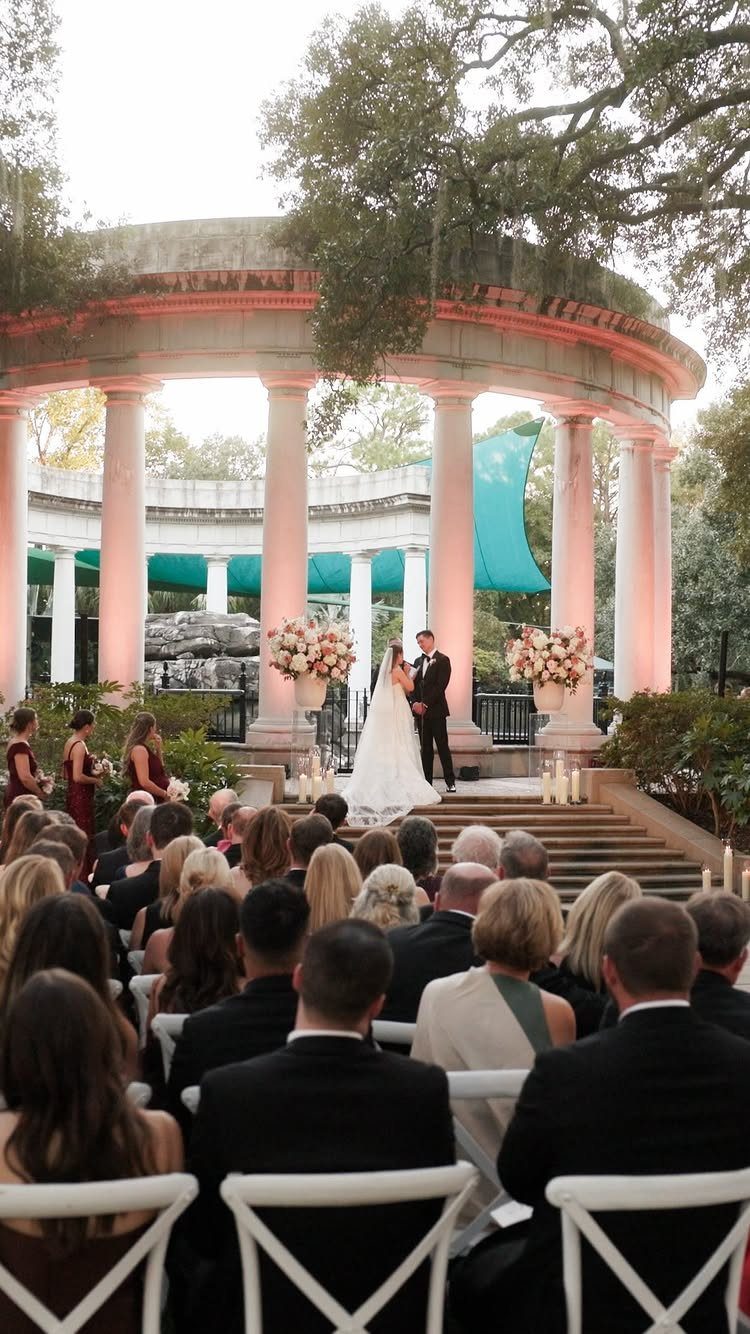 Wedding ceremony at a venue with a classical white column rotunda and guests.