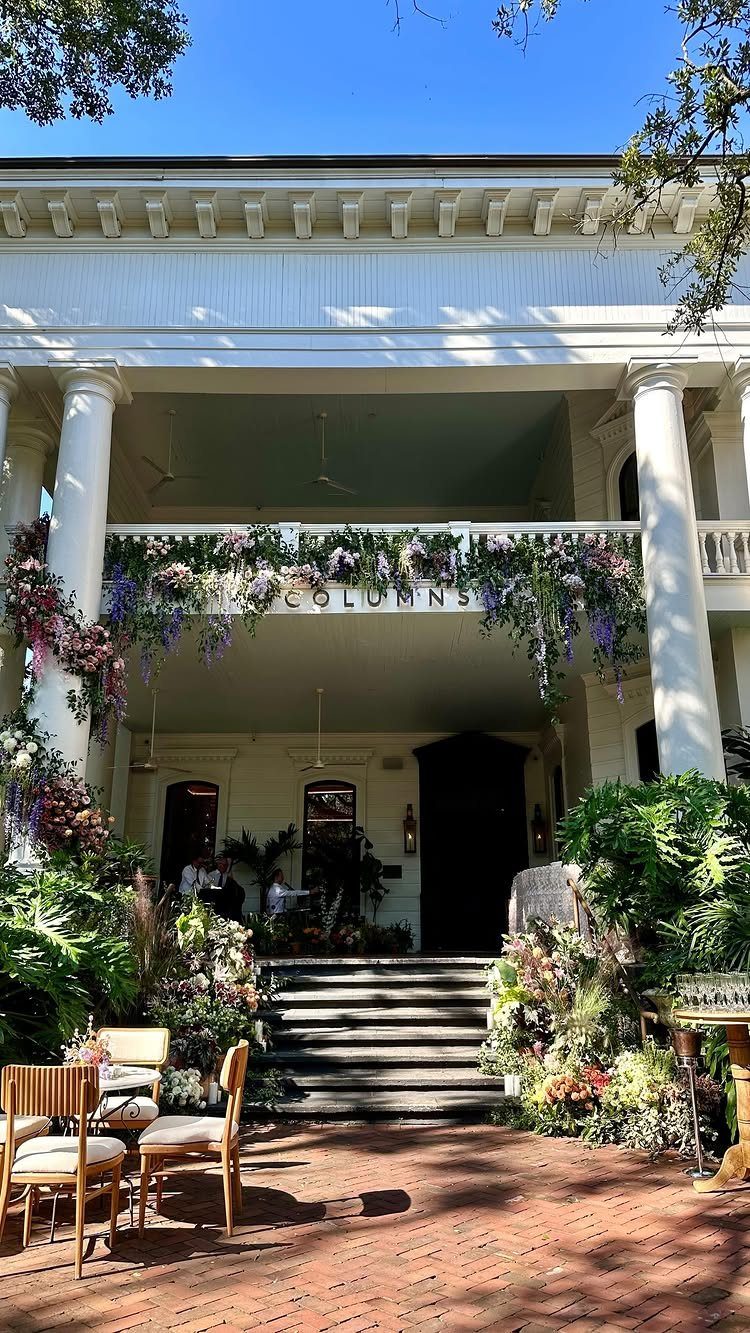 White historic building with large columns and floral decorations on the porch balcony.