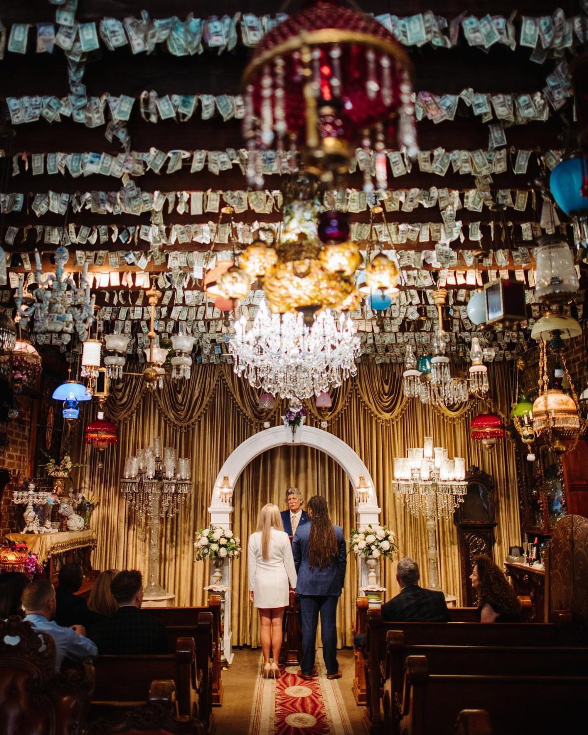 Wedding ceremony in a chapel with gold curtains and banknotes hanging from the ceiling