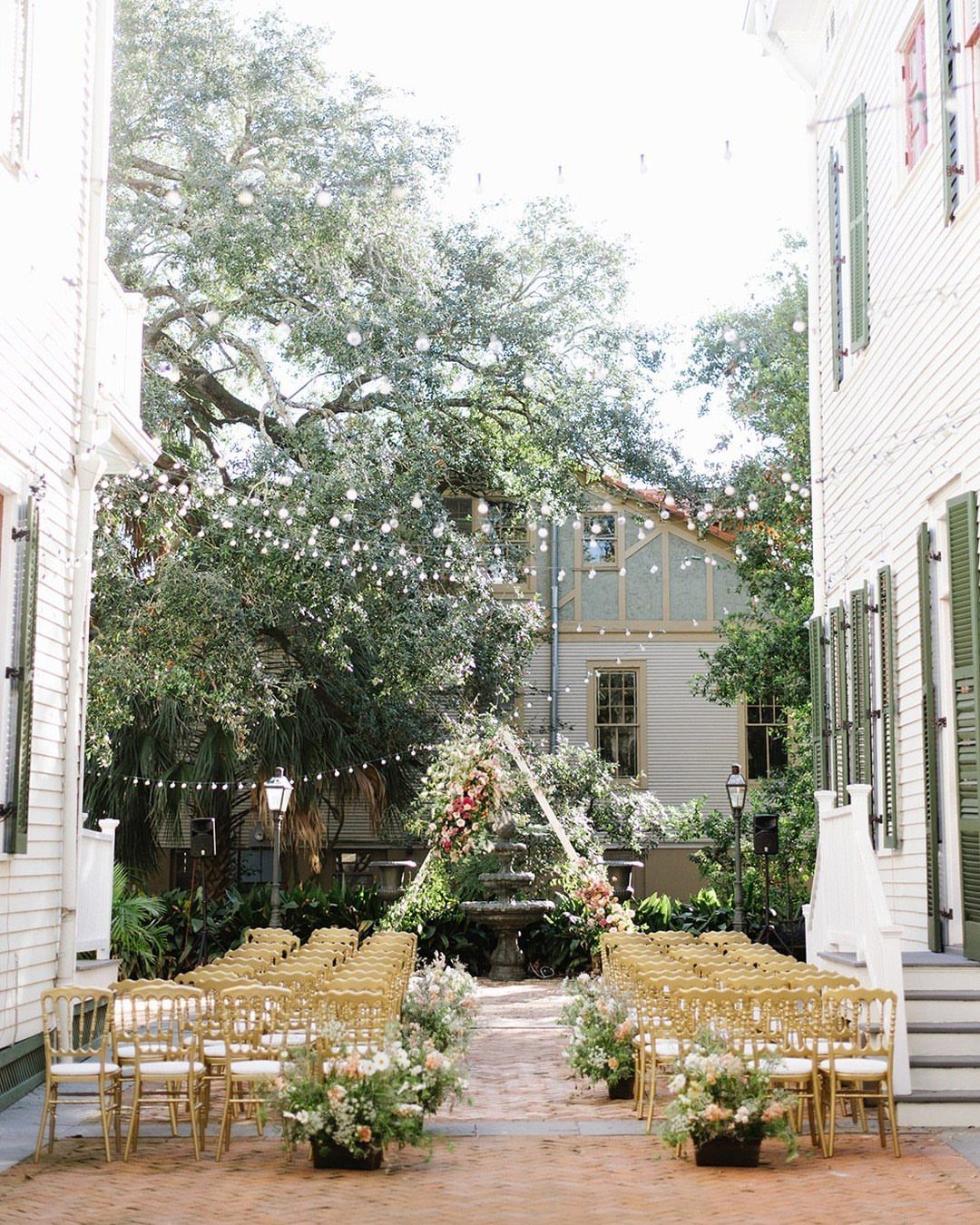 Wedding ceremony setup with gold chairs and floral arch in a historic courtyard