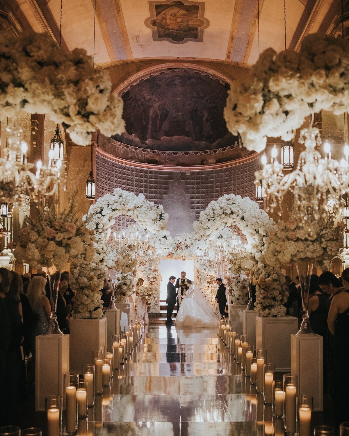 Bride and groom at the altar of a church decorated with white flowers and candles.