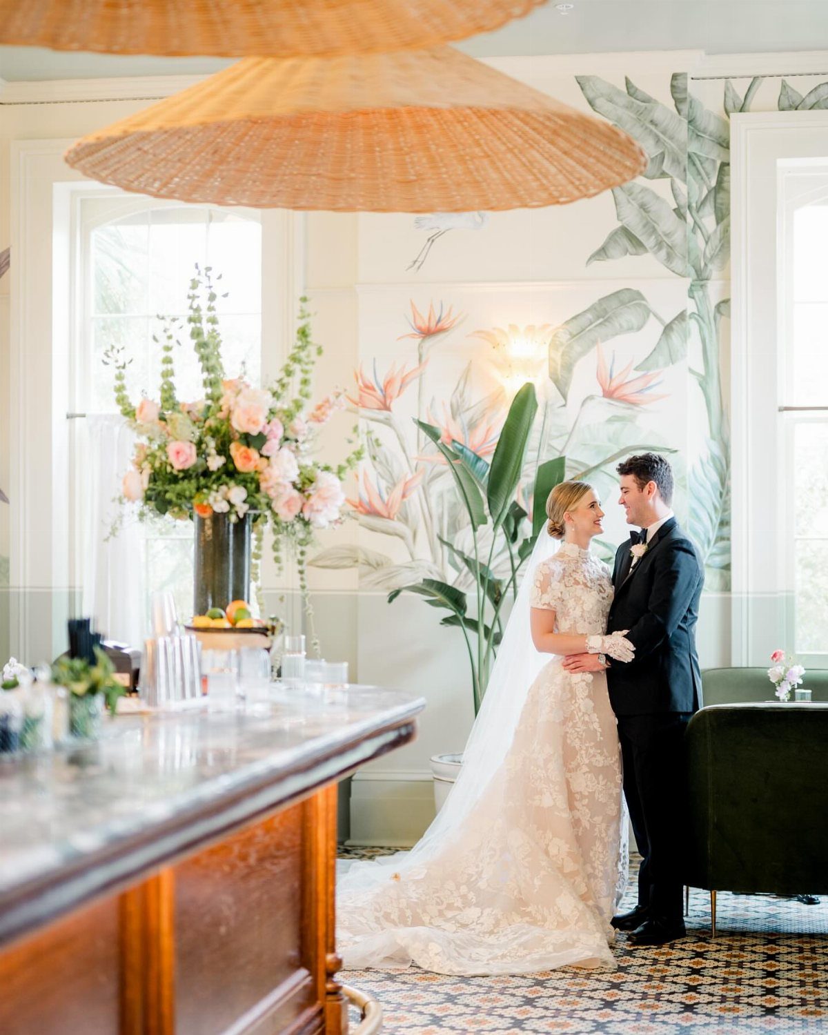 Bride and groom posing in a vintage hotel room with tropical wall murals.