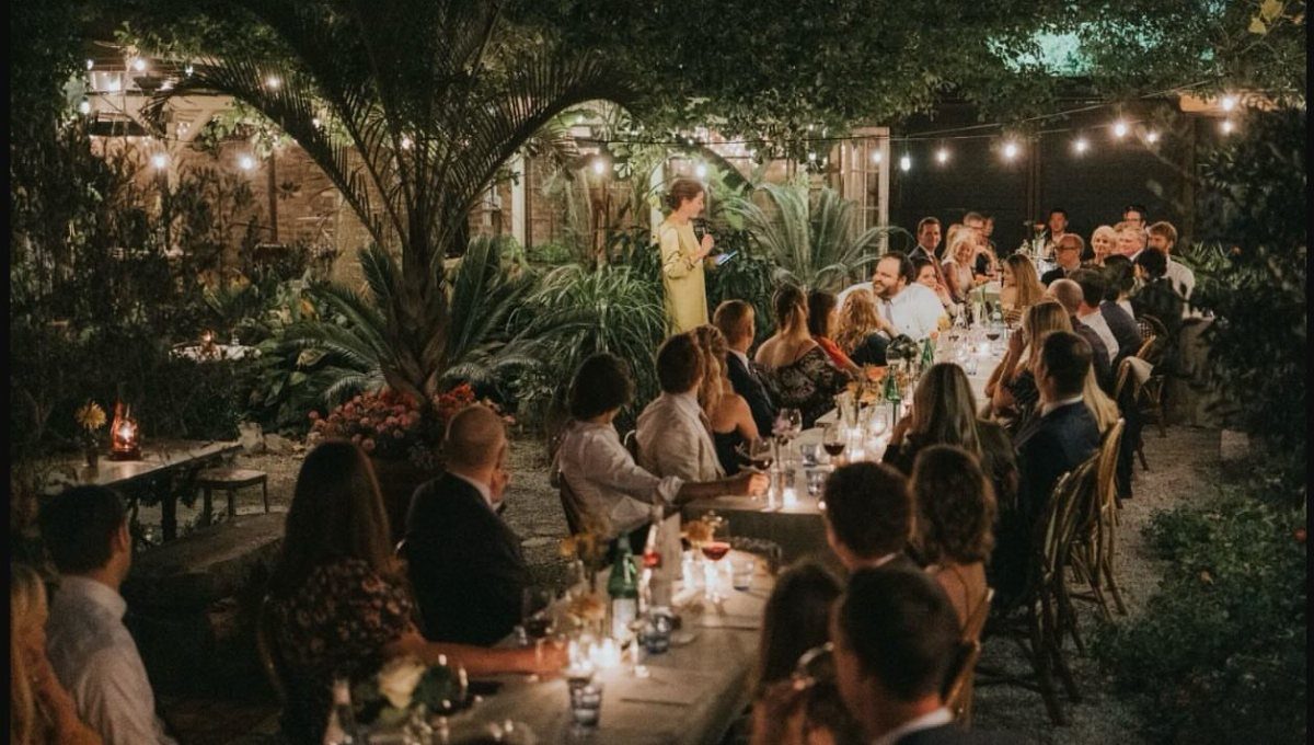 Dinner party in a lush outdoor courtyard with string lights and tropical greenery