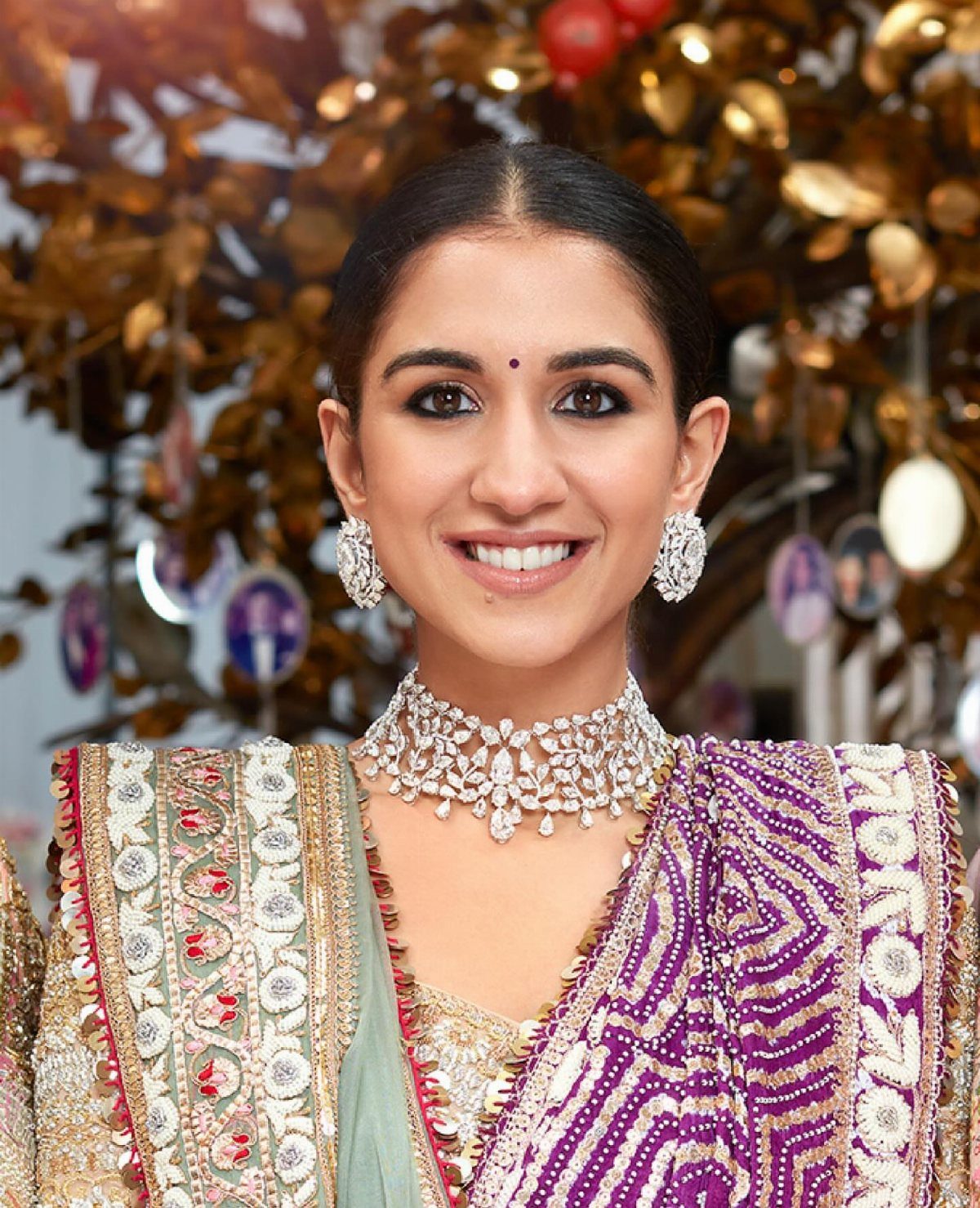 Woman in a purple embroidered lehenga wearing a diamond choker and matching earrings.