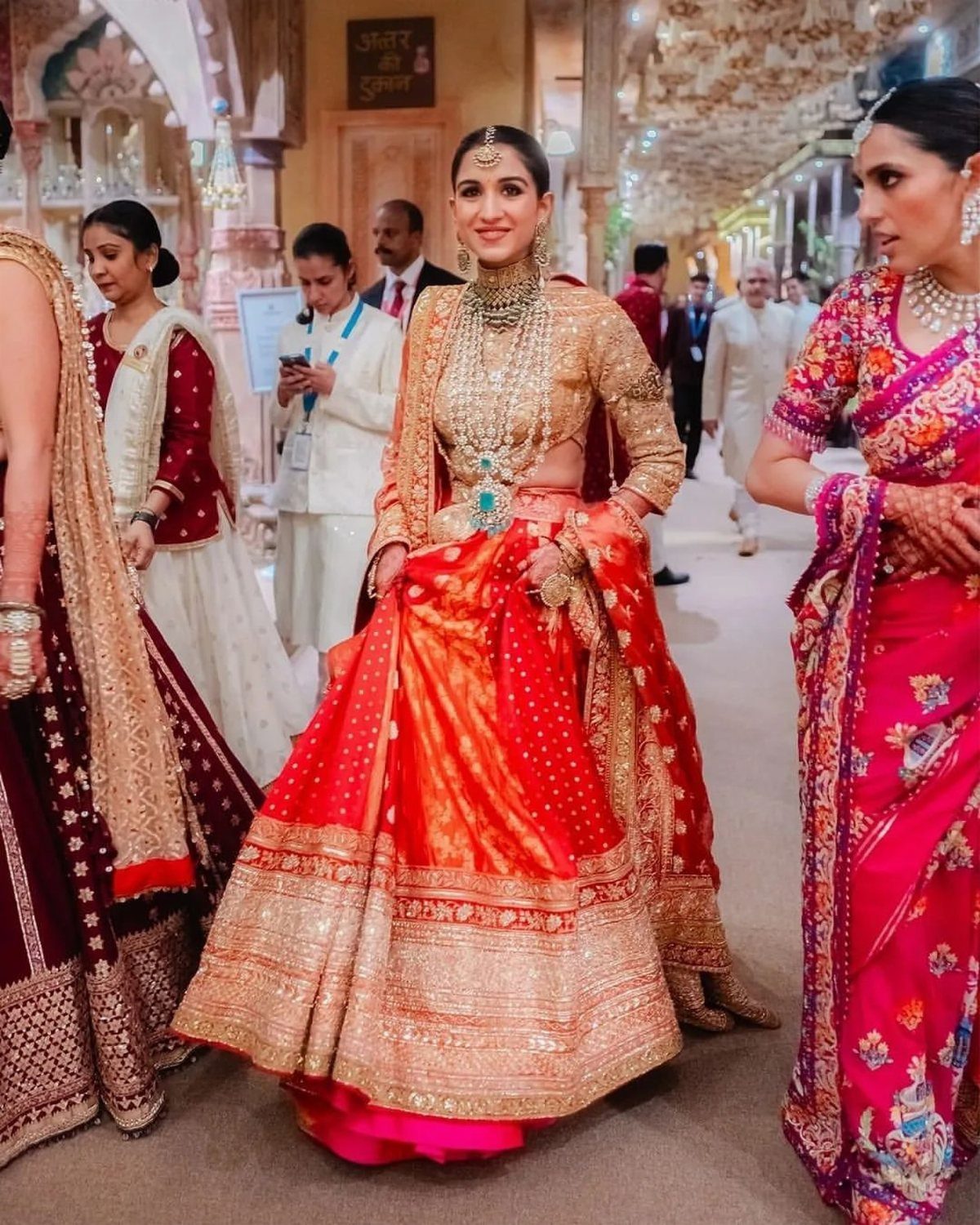 Woman in a red and orange Banarasi brocade lehenga with gold jewelry.