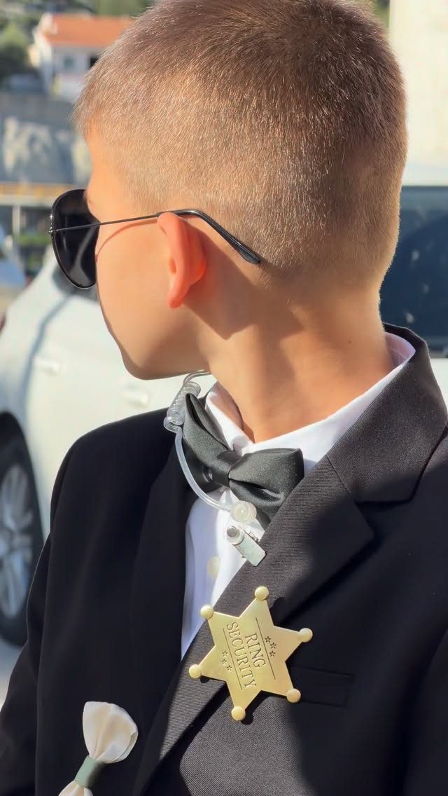 Young boy in a black suit and bow tie wearing a ring security badge.