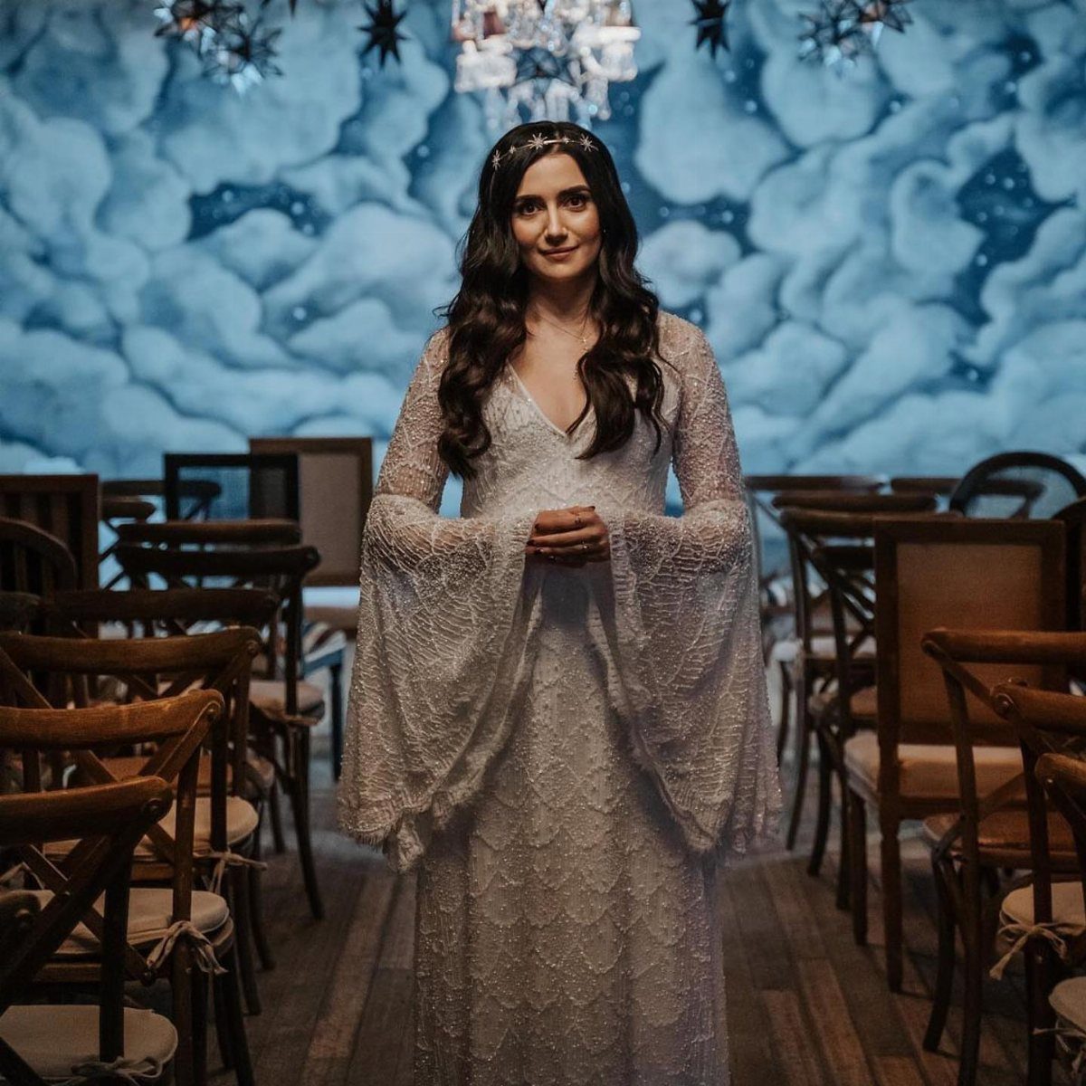 Woman in a white lace wedding dress with bell sleeves and star headband.