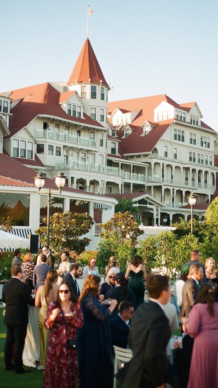 Historic Hotel Del Coronado with guests in formal wear gathering on the lawn.