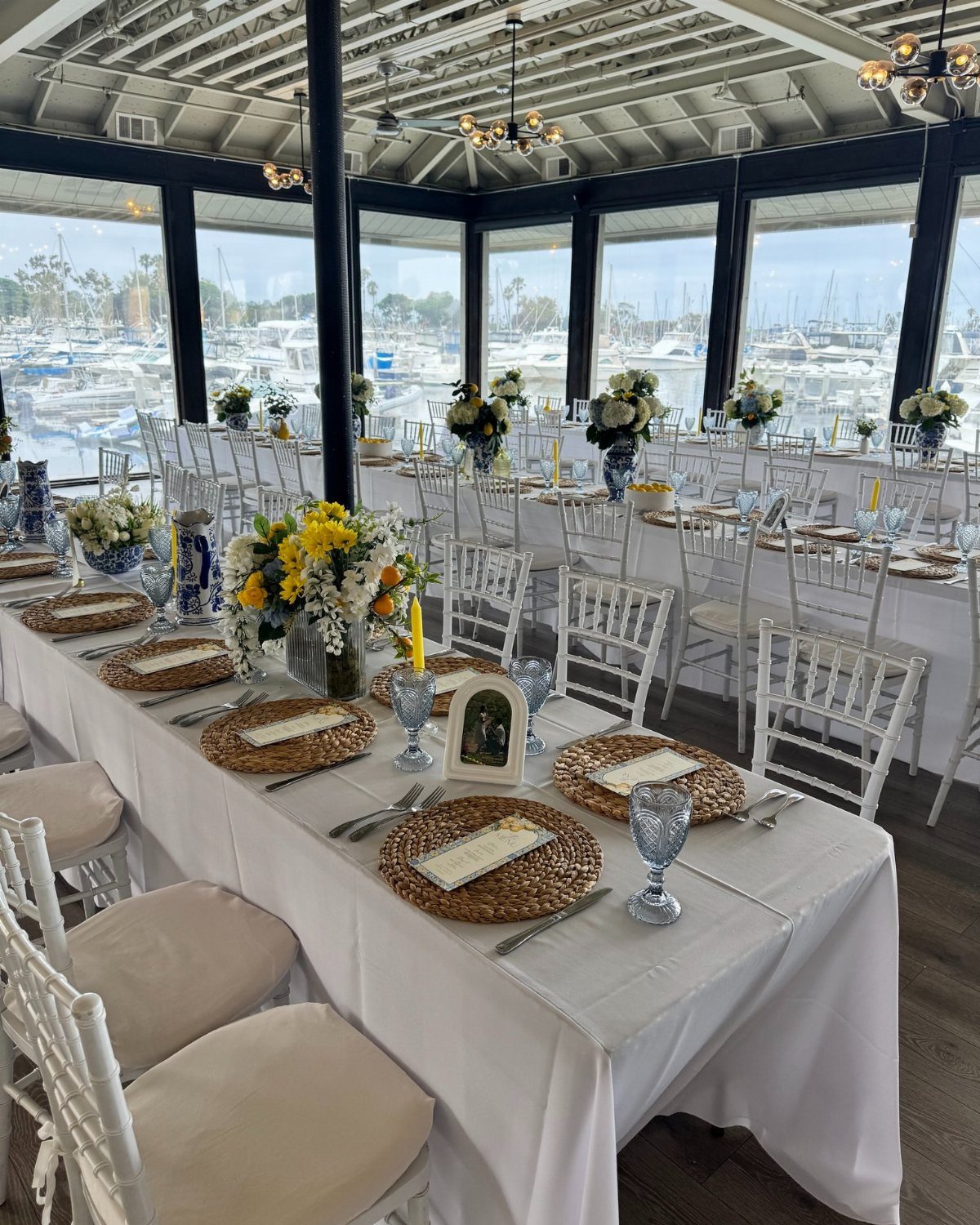 Wedding reception table setting with yellow flowers overlooking a marina with many boats