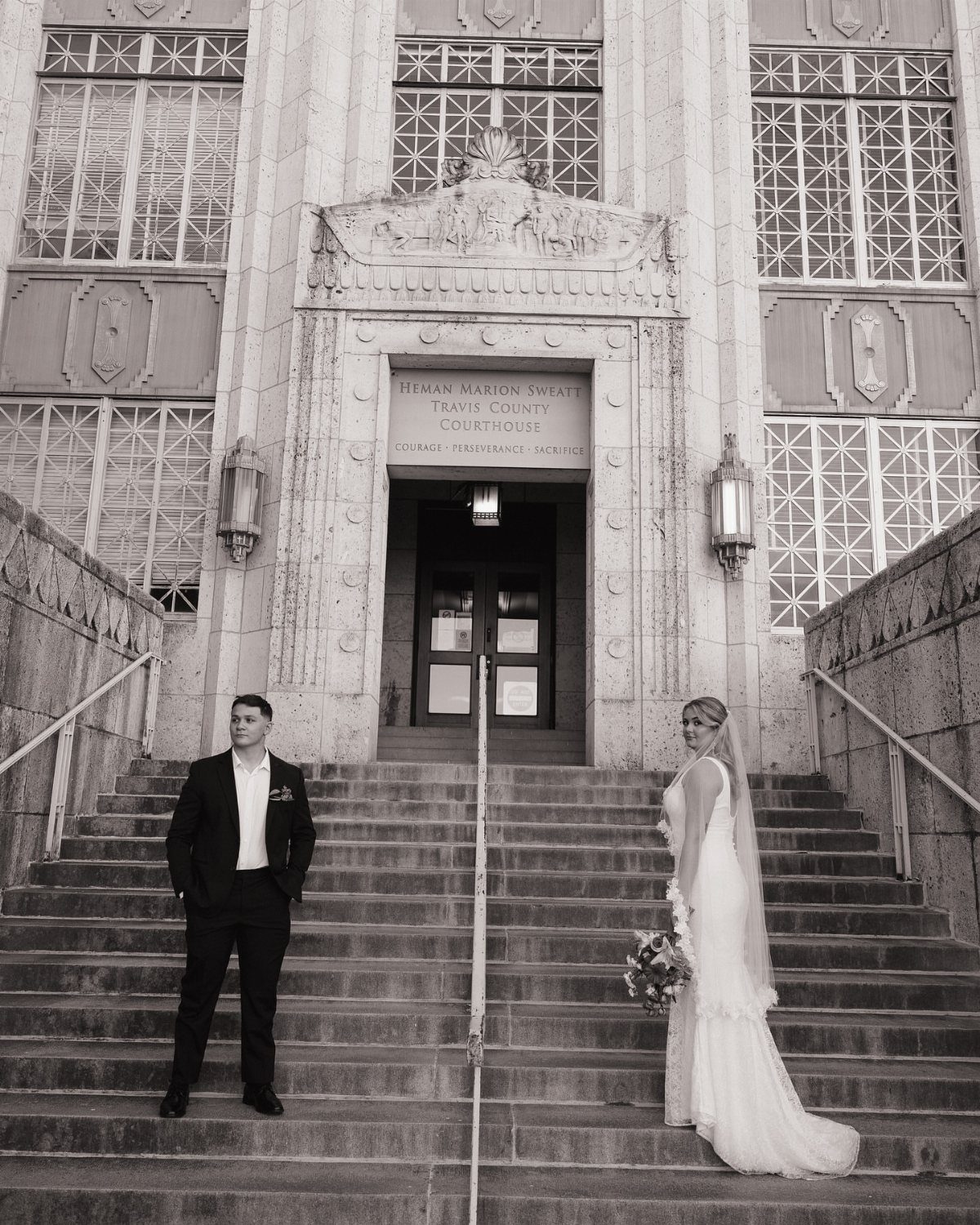 Bride and groom standing on the stone steps of the Travis County Courthouse.