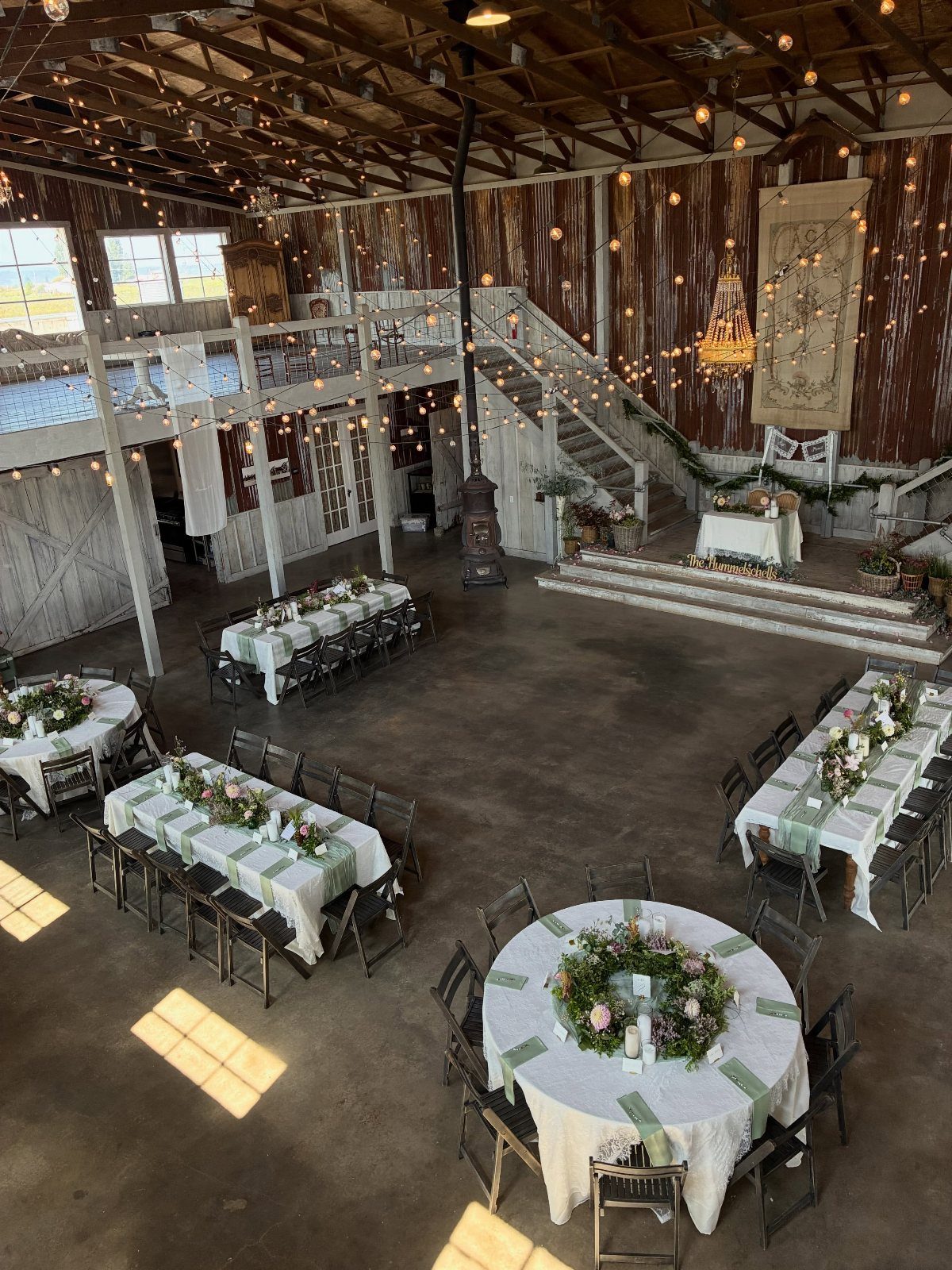 Rustic barn wedding venue with decorated dining tables and warm string lighting.