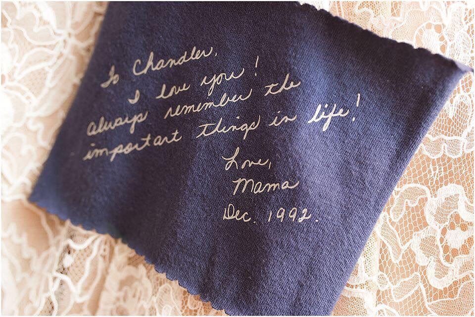 Blue fabric scrap with handwritten note sewn into white lace wedding dress.