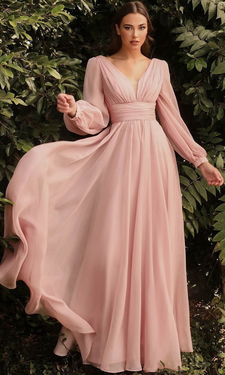 Woman in a flowing light pink maxi dress with voluminous bishop sleeves outdoors.