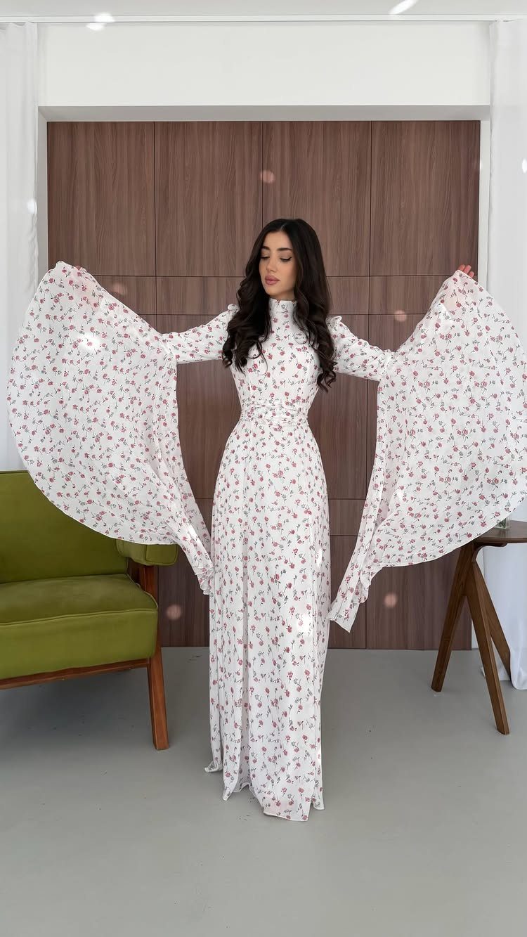 Woman wearing a white floral maxi dress with dramatic wide bell sleeves.