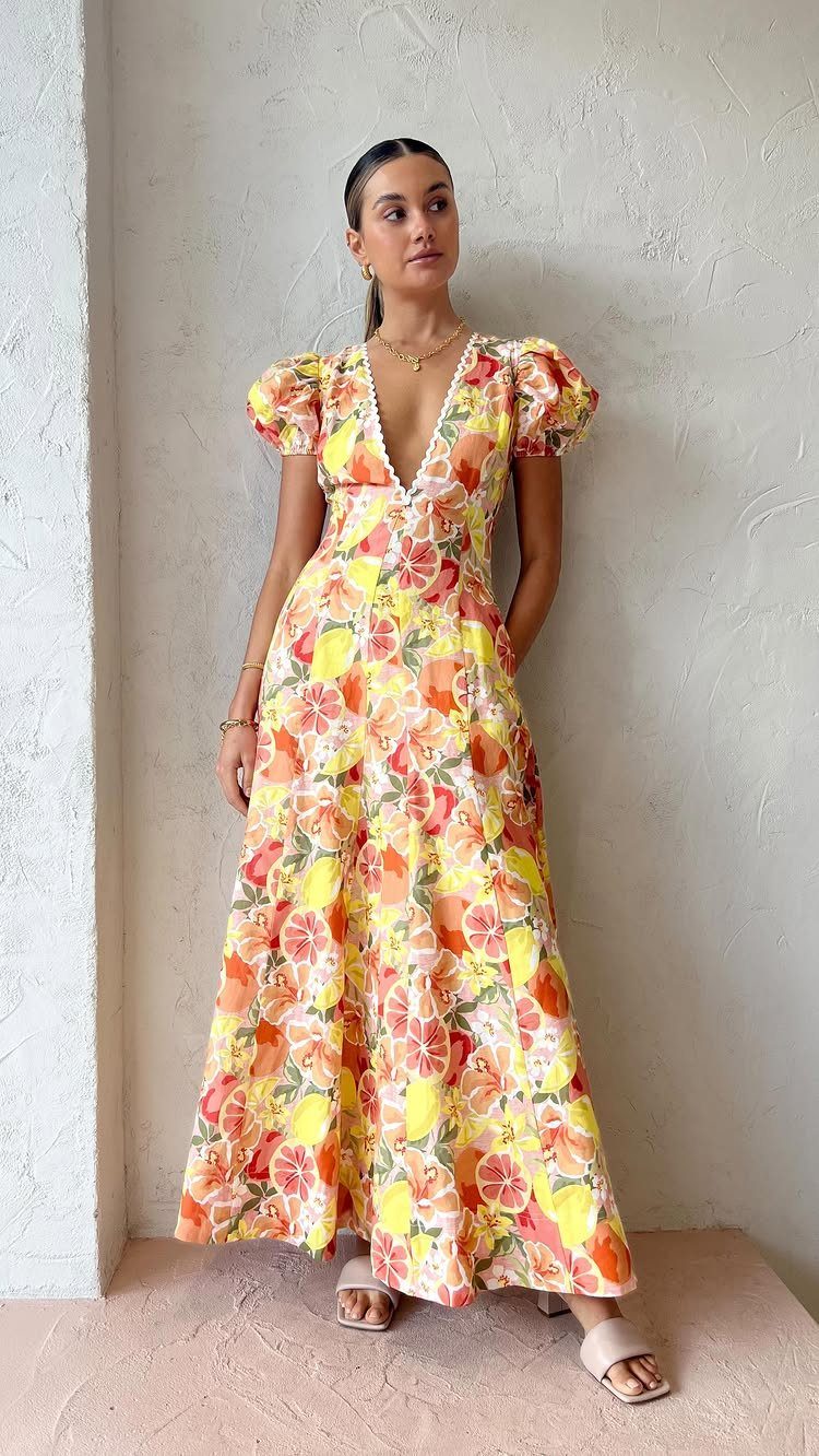 Woman in a yellow floral maxi dress with puffed sleeves and V-neckline.