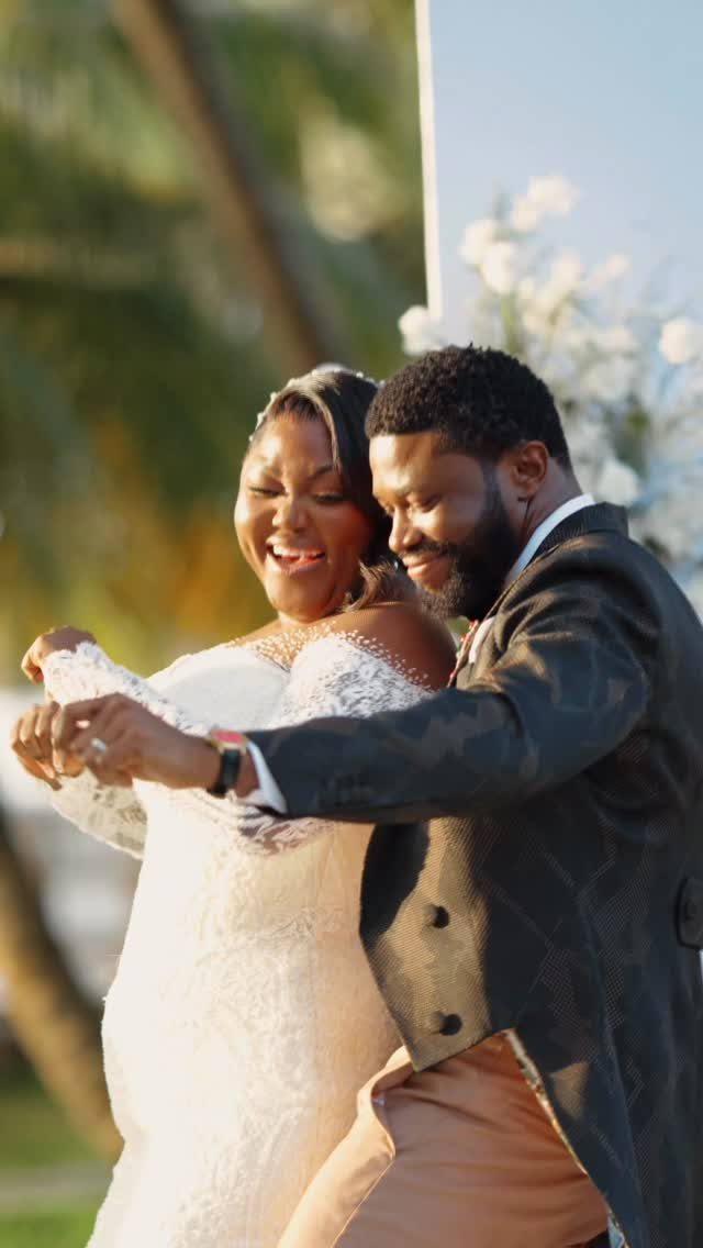 Smiling couple dancing outdoors, woman wearing a white lace off-the-shoulder wedding dress.