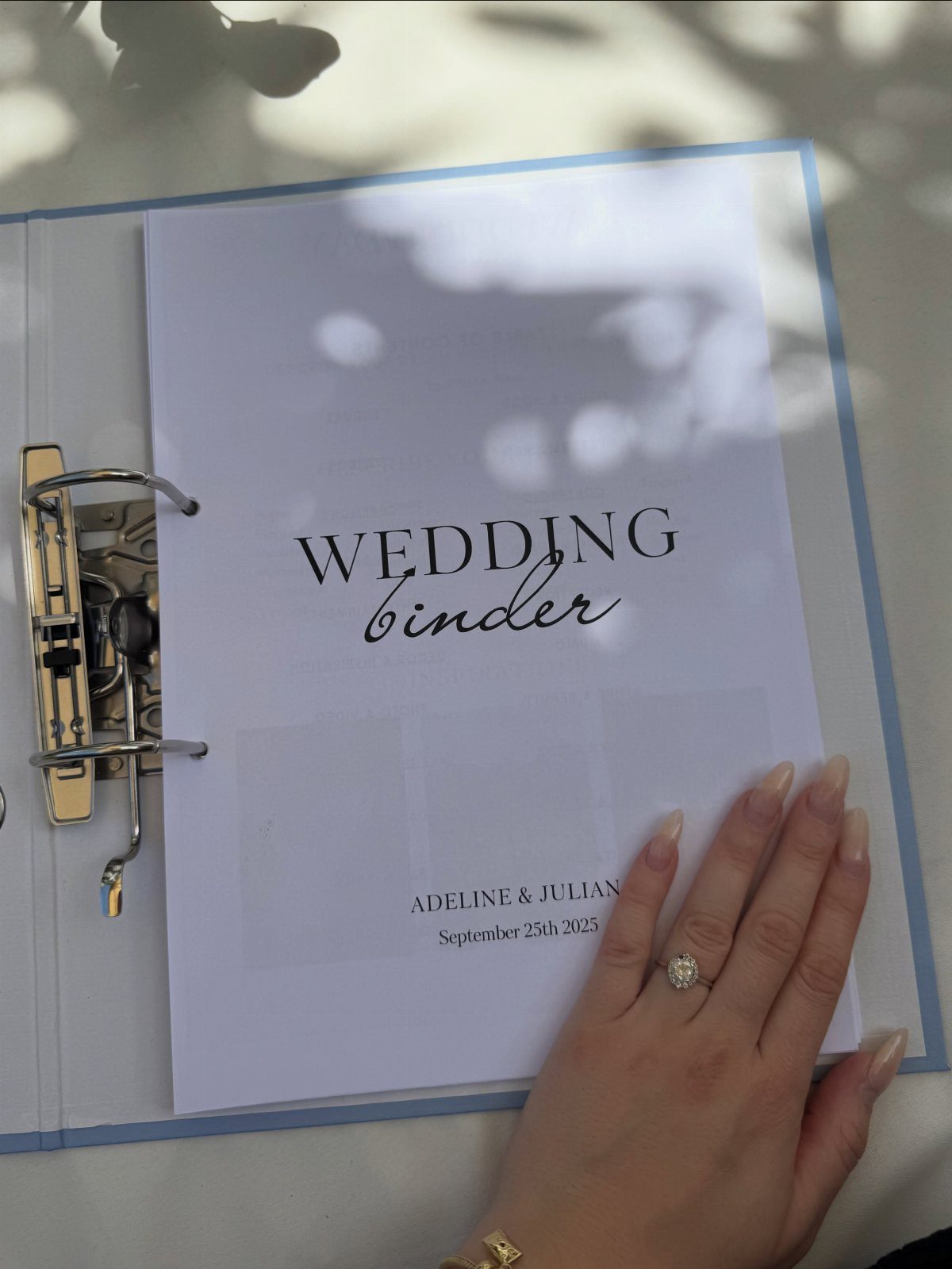 Wedding binder with personalized cover page and a woman's hand wearing an engagement ring