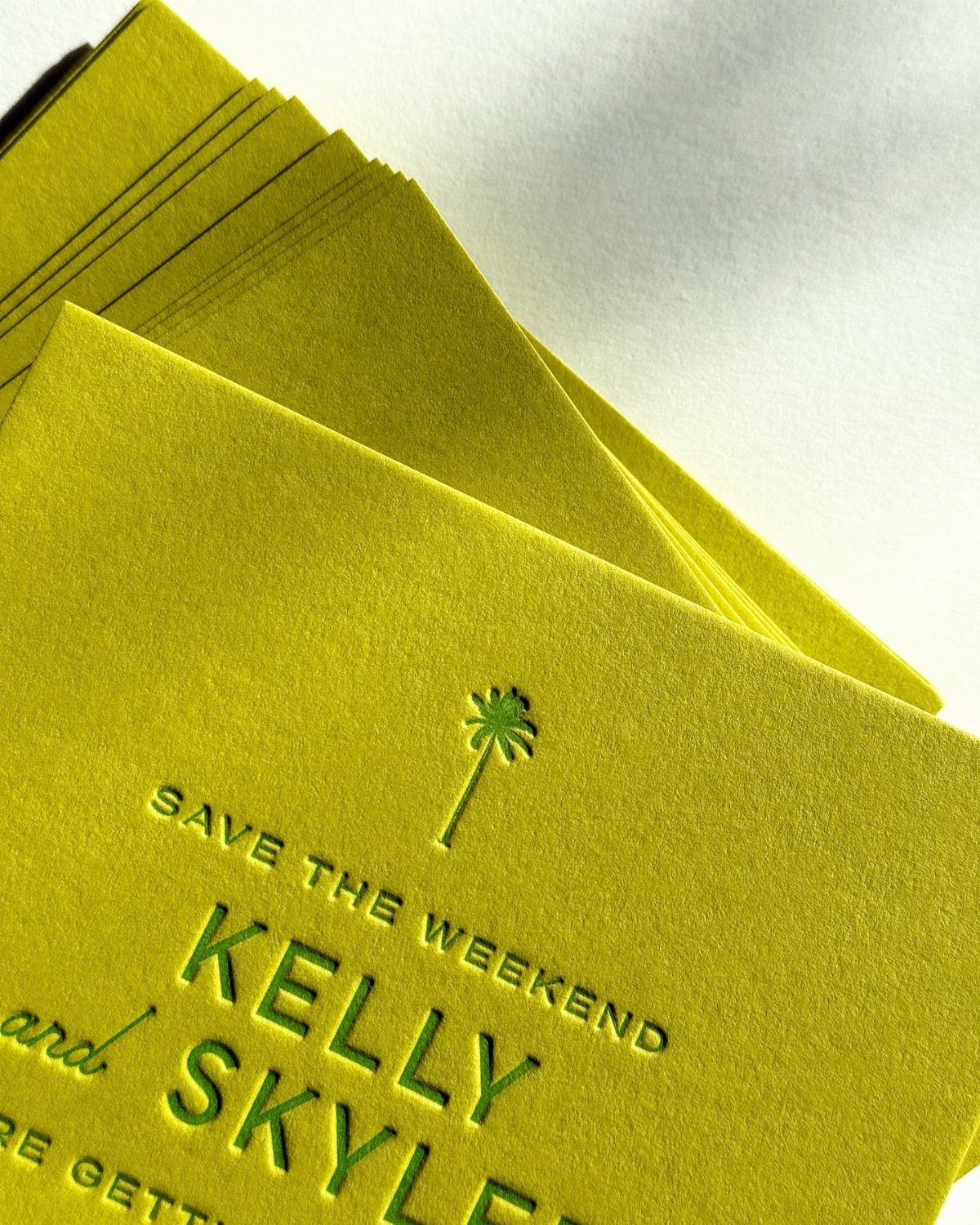 Chartreuse green wedding invitations with embossed text and a small palm tree icon.
