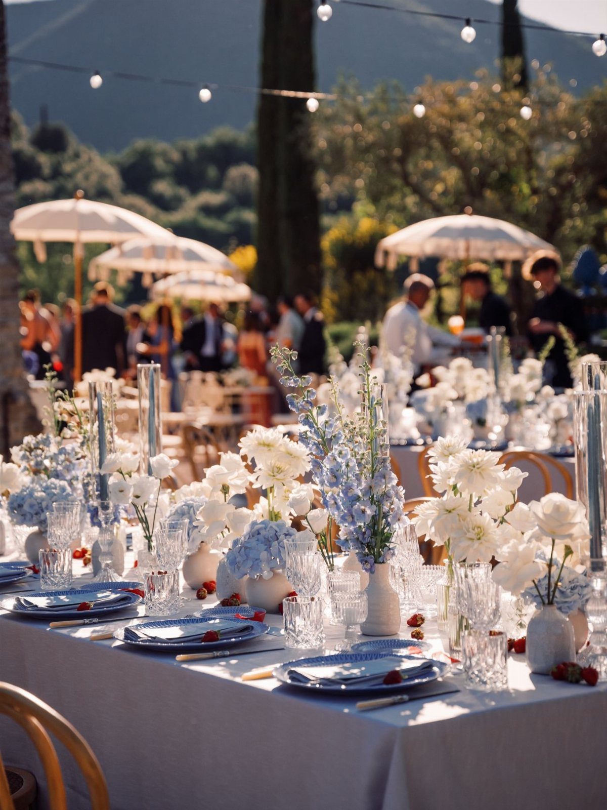 Wedding table setting with dusty blue linens and ivory and blue floral centerpieces.