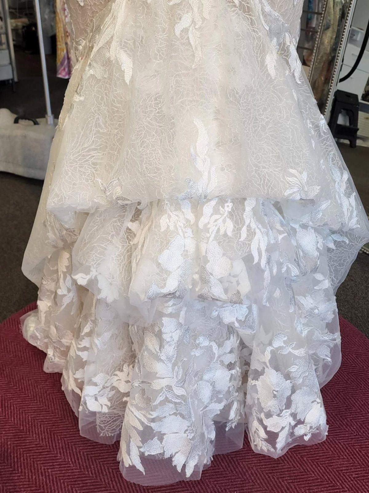 White lace wedding dress with a multi-layered French bustle gathered at the back.