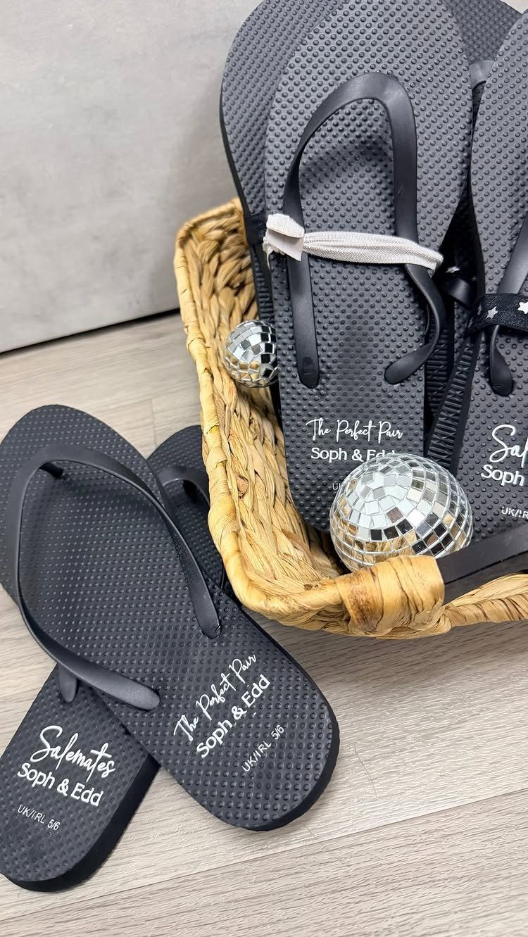 Black personalized flip-flops in a wicker basket with small disco ball decorations.