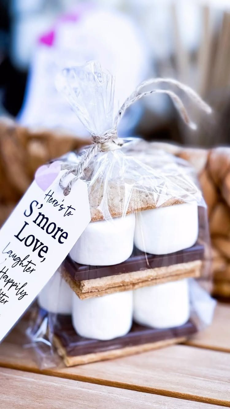 S'mores kits with marshmallows, chocolate, and graham crackers in a clear tied bag.