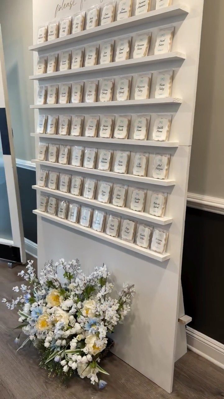 White tiered display shelf with individually wrapped cookie place cards and floral arrangement.