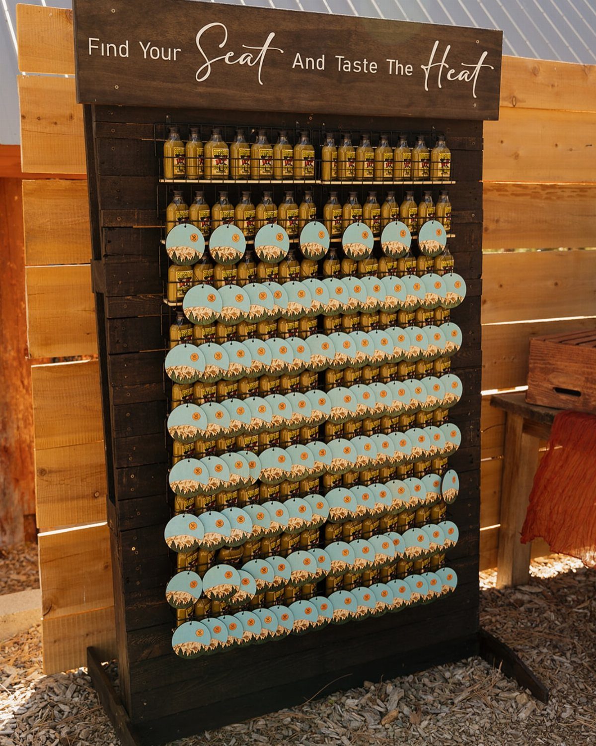 Mini hot sauce bottles with blue labels on a wooden display rack.