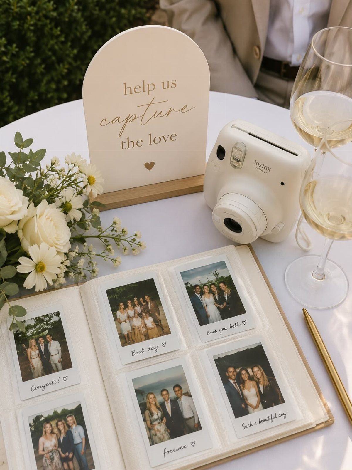 Instax camera and guest book with Polaroid wedding photos on a decorated table.