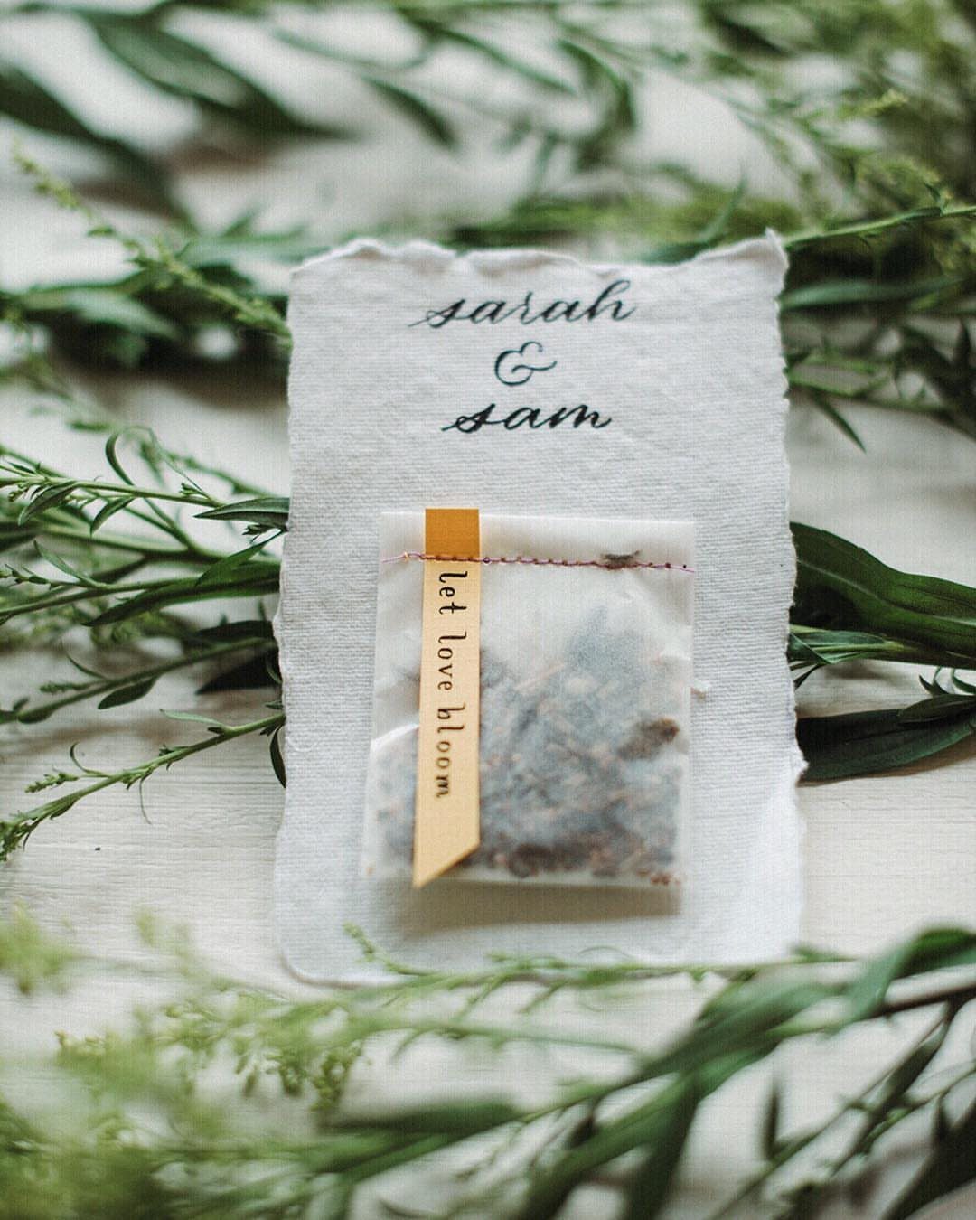Seed packet with yellow ribbon on a personalized fabric card among green leaves